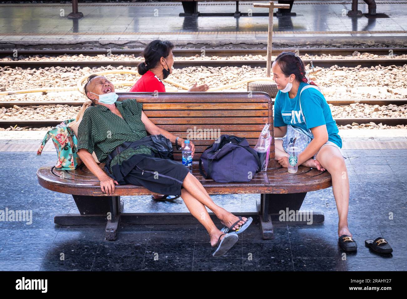 Thailändische Händler lachen, als sie auf einen Zug vom Hua Lamphong Bahnhof in Bangkok warten Stockfoto