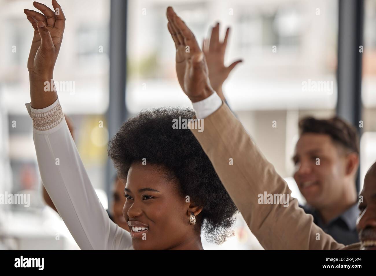 Glückliche Geschäftsleute, schwarze Frau oder Hände hoch bei Seminaren für die Teilnahme oder das Erlernen von Fähigkeiten. Abstimmen, lächeln oder das Publikum stellt Fragen in der Gruppe Stockfoto