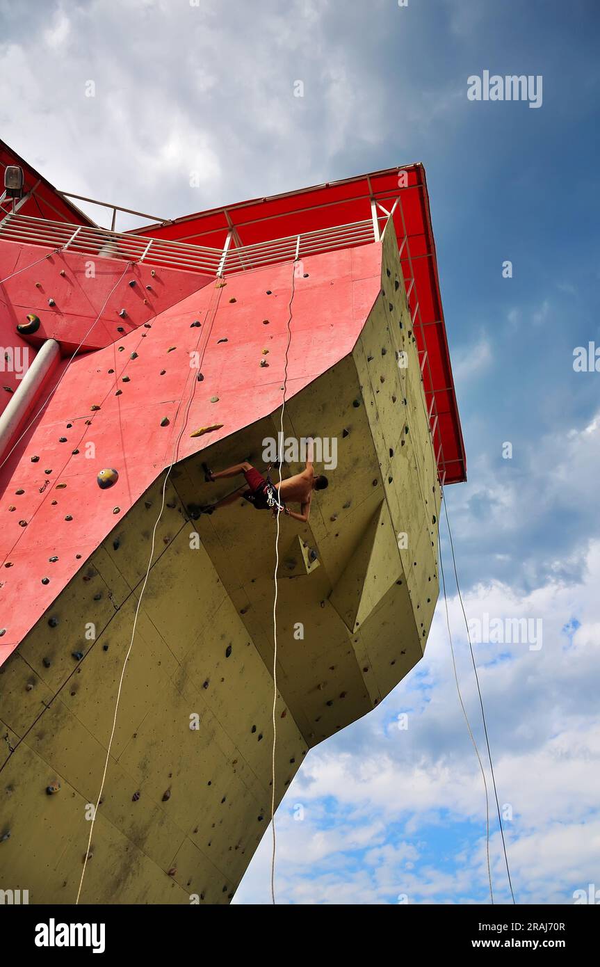 Ein muskulöser Mann, der auf eine große Wand klettert Stockfoto