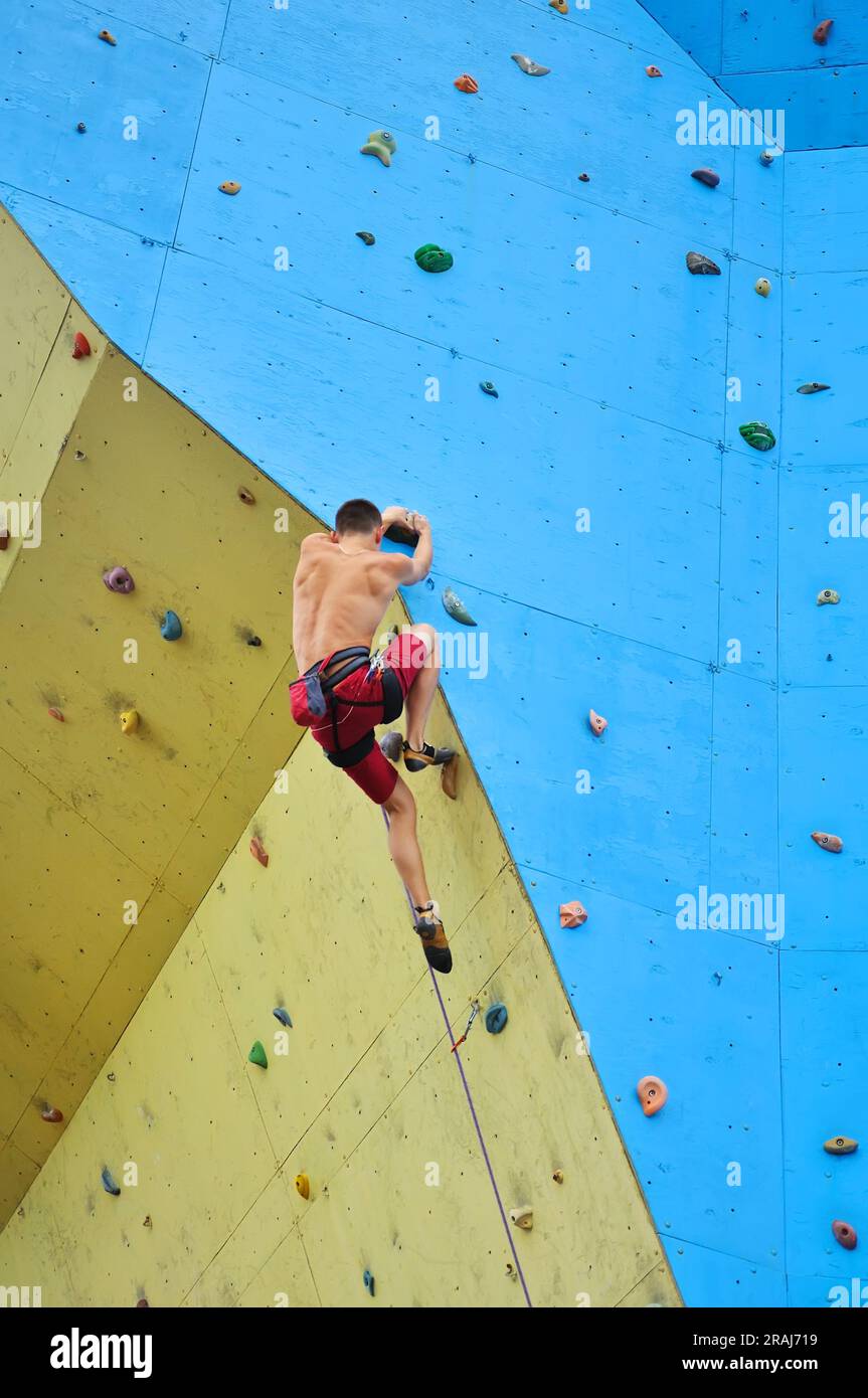 Junger Kletterer klettert auf eine Wand Stockfoto