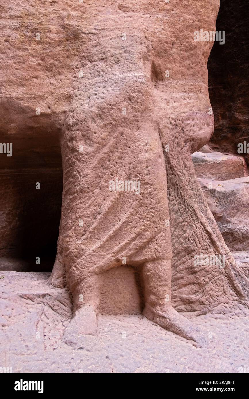 Eine kopflose untere Hälfte eines Körpers, der in die Felsen der antiken Stadt Petra, Jordanien, geschnitten wurde. Stockfoto