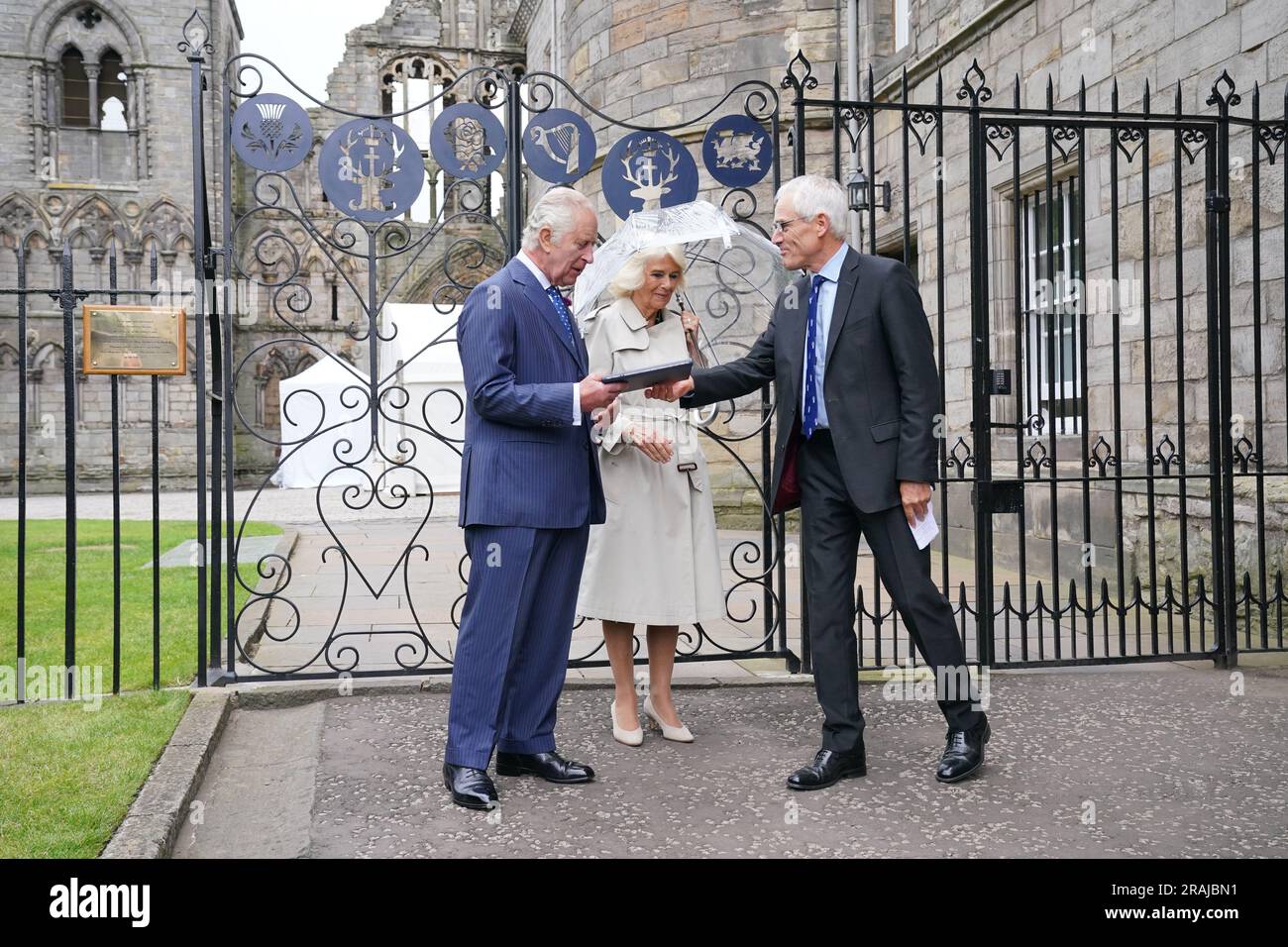 König Karl III. Und Königin Camilla erhalten ein Buch mit Lederbindung über die Geschichte des Holyroodhouse vom Moderator der Obersten Konstallen, Roderick Urquhart, während sie die neuen Jubiläumsgates besuchen, die am Eingang zum Abbey Yard installiert wurden, um das Platinjubiläum von Königin Elisabeth II. Zu feiern, Im Palast von Holyroodhouse, Edinburgh. Bilddatum: Dienstag, 4. Juli 2023. Stockfoto