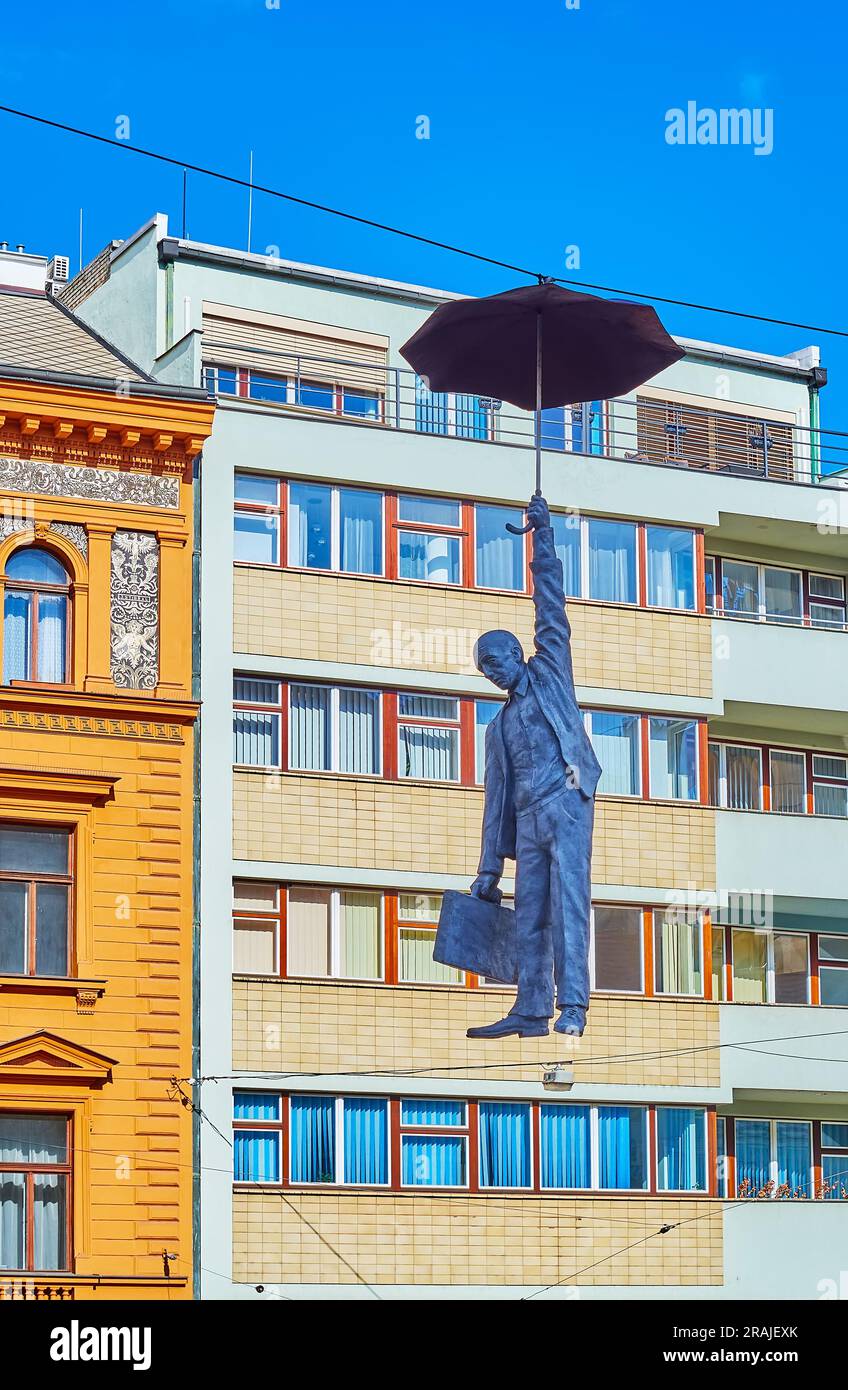 PRAG, TSCHECHIEN - 5. MÄRZ 2022: Hängender Regenschirmmann oder Skulptur mit geringer Unsicherheit von Michal Trpak gegen das lebende Haus, am 5. März in Prag Stockfoto