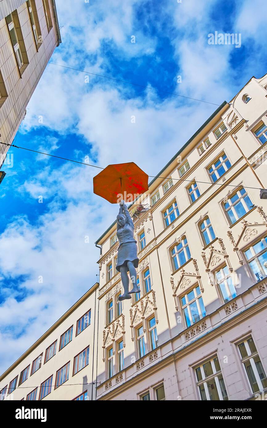 PRAG, TSCHECHIEN - 5. MÄRZ 2022: Hängende Regenschirmfrau oder leichte Ungewissheit Installation von Michal Trpak gegen das Haus und den blauen Himmel, am 5. März Stockfoto