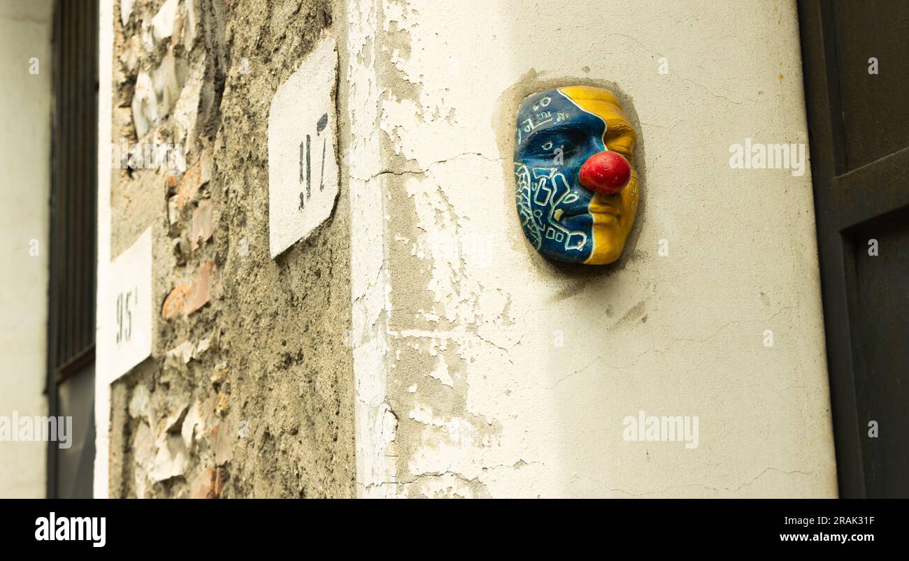 Farbige Gipsmaske, Gesicht eines Clowns, an einer Straßenwand Stockfoto