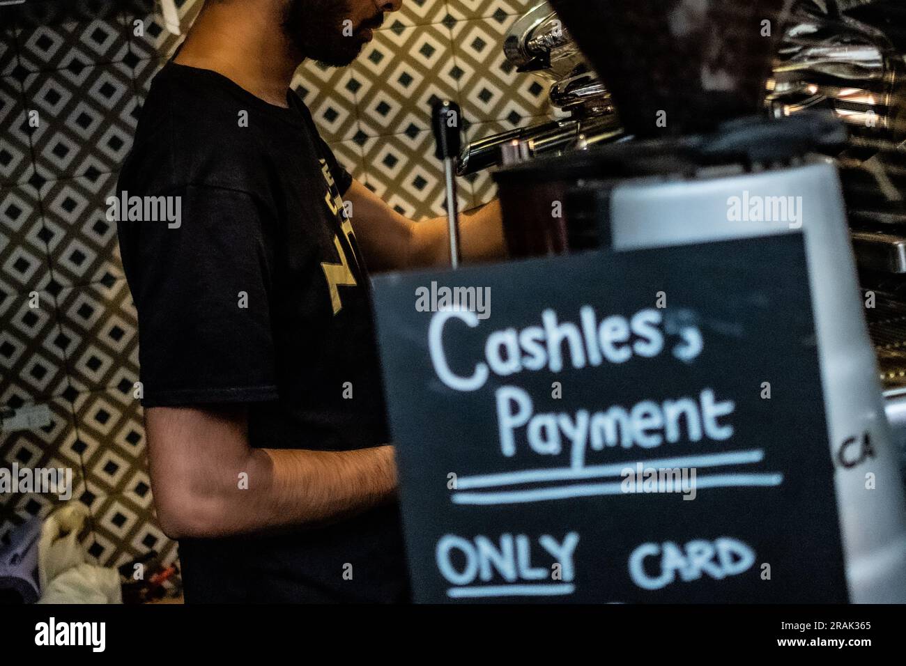 London - Juni 2023: Eine Person macht einen Kaffee in einem Londoner Café mit einem Schild mit der Aufschrift „Only Card“ und „Cashless payment“- Stockfoto
