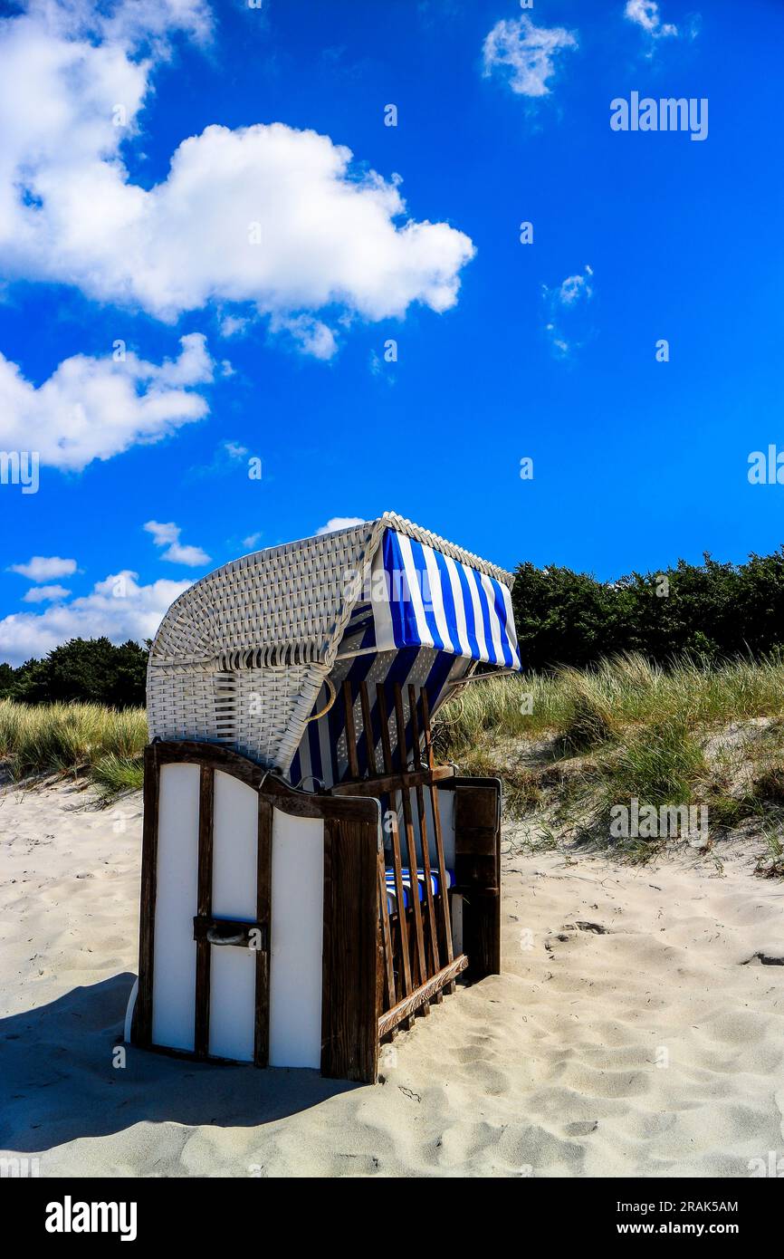 Leerer Ostsee-Rattan-Liegestuhl im Sand Stockfoto
