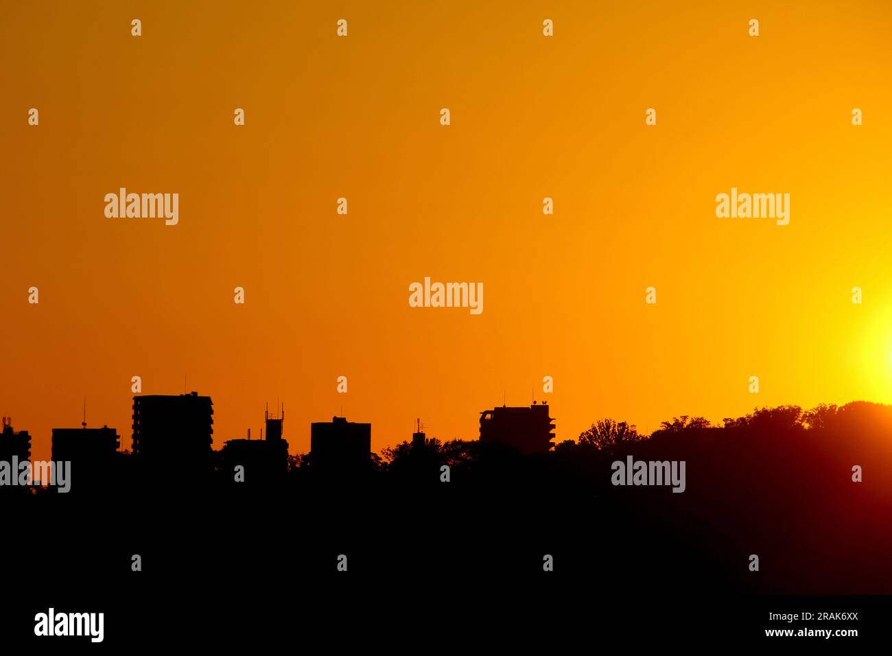 Ein farbenfroher Sonnenuntergang mit Gebäude und Baumsilhouette Stockfoto