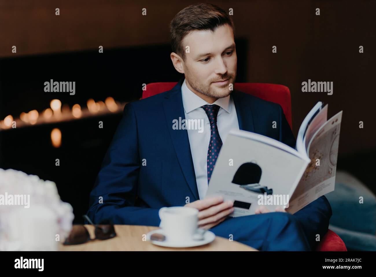 Seriöser Unternehmer liest Zeitschrift, Café, formeller Anzug, Dinnerpause. Business- und Lifestyle-Konzept. Stockfoto
