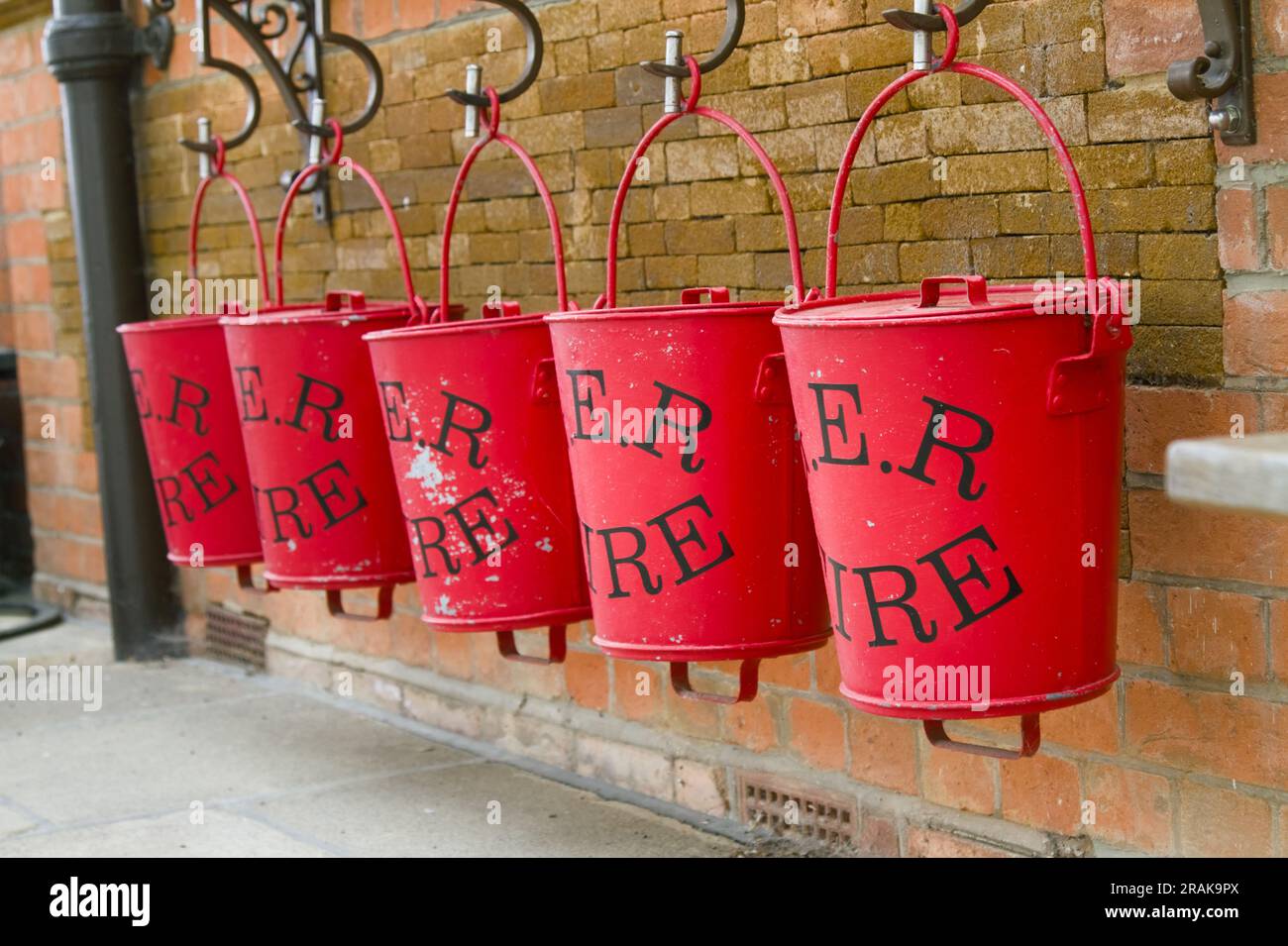 Linie von galvanisierten rot lackierten Feuerlöscheimern mit Sand auf der Plattform der stillgelegten Royal Wolferton Station, Wolferton, England, Großbritannien Stockfoto