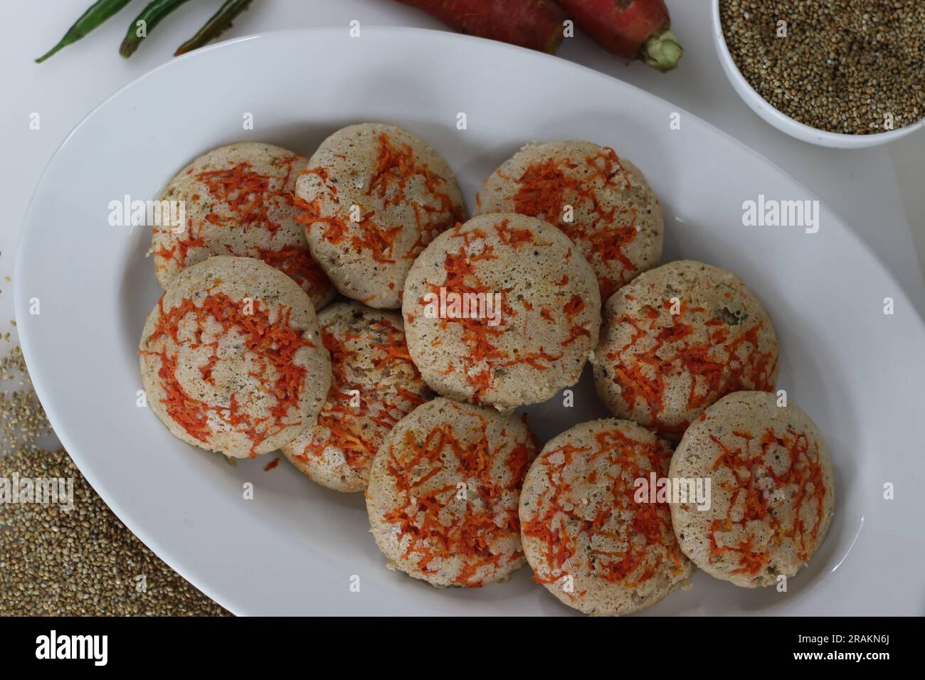 Karotten-Bajra unschuldig. Gedünsteter, herzhafter Reiskuchen aus einem Teig fermentierter, geschälter schwarzer Linsen und nicht polierter Perlhirse mit frisch geriebenem Karr Stockfoto