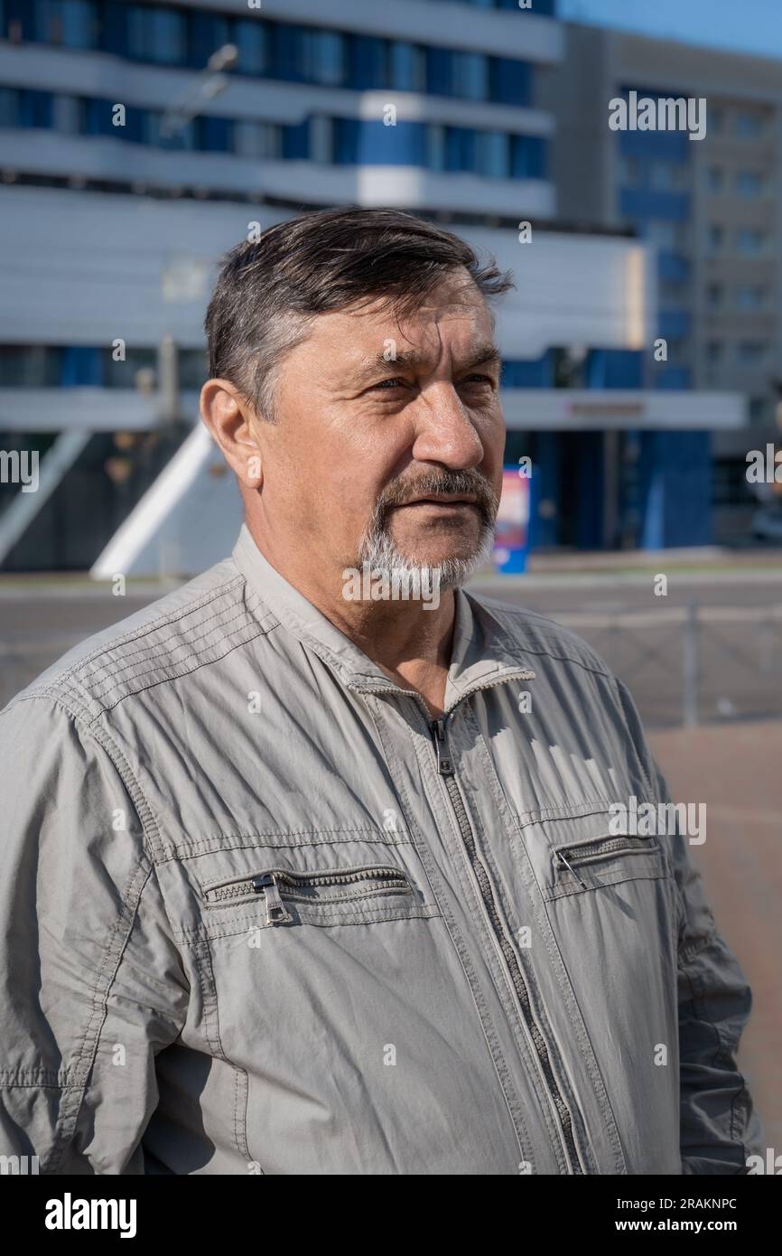 Porträt eines grauhaarigen 70-jährigen Mannes mit Bart und Schnurrbart. Ein selbstbewusster, seriöser Mann vor dem Hintergrund eines Geschäftszentrums. Stockfoto