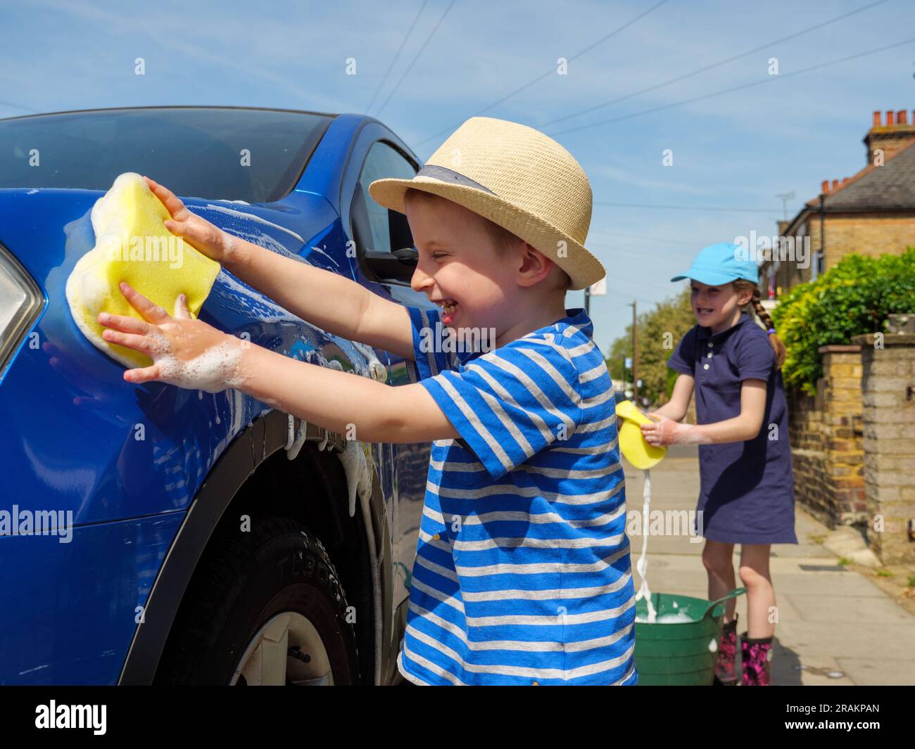 Zwei Kinder, die Spaß beim Autowaschen haben Stockfoto