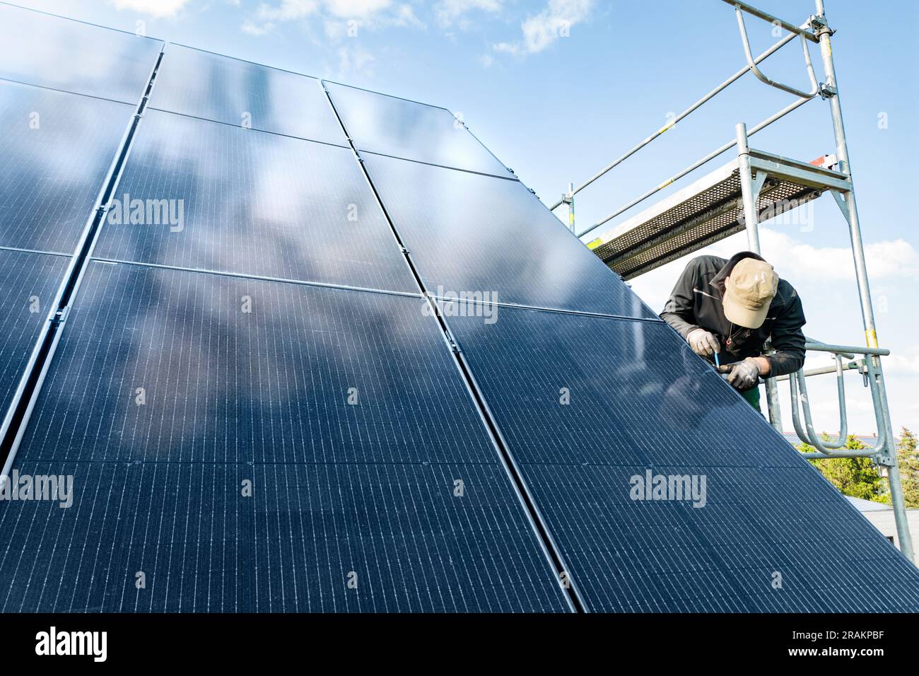 Techniker, der an einem Solarpaneel auf dem Dach eines Hauses arbeitet Stockfoto