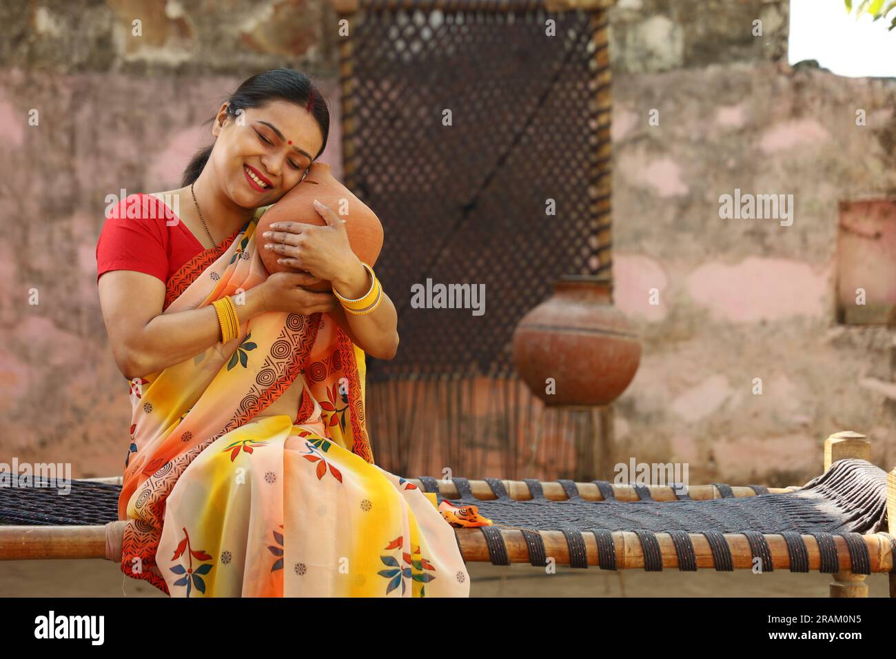 Glückliche ländliche indische Frauen in Saree mit der Piggy Bank in der Hand. Eine Frau mit Ehrgeiz zeigt ihre Liebe zu gespartem Geld für ihre Zukunft, wenn sie ins Ausland geht. Stockfoto