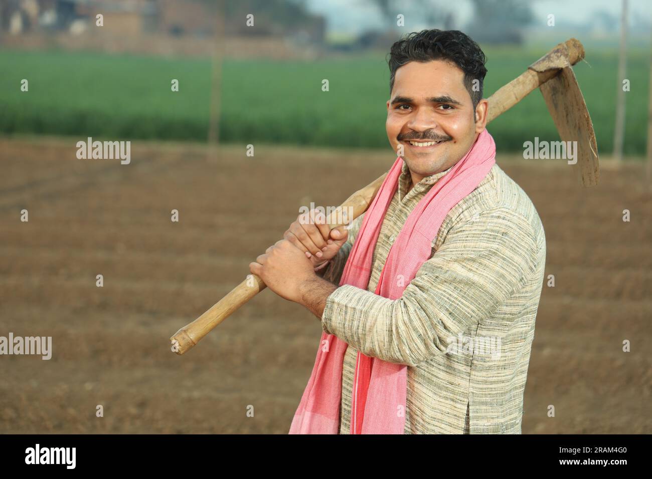 Porträt eines indischen glücklichen Landwirts, der das Feld an einem Tag manuell pflügt. Halten Sie das landwirtschaftliche Werkzeug in der Hand. Schaufel mit Grabwerkzeug und Hacke in der Hand. Stockfoto