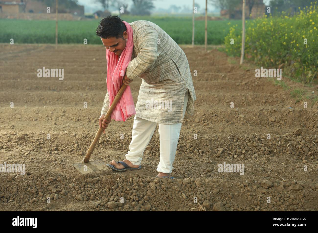 Porträt eines indischen glücklichen Landwirts, der das Feld an einem Tag manuell pflügt. Halten Sie das landwirtschaftliche Werkzeug in der Hand. Schaufel mit Grabwerkzeug und Hacke in der Hand. Stockfoto