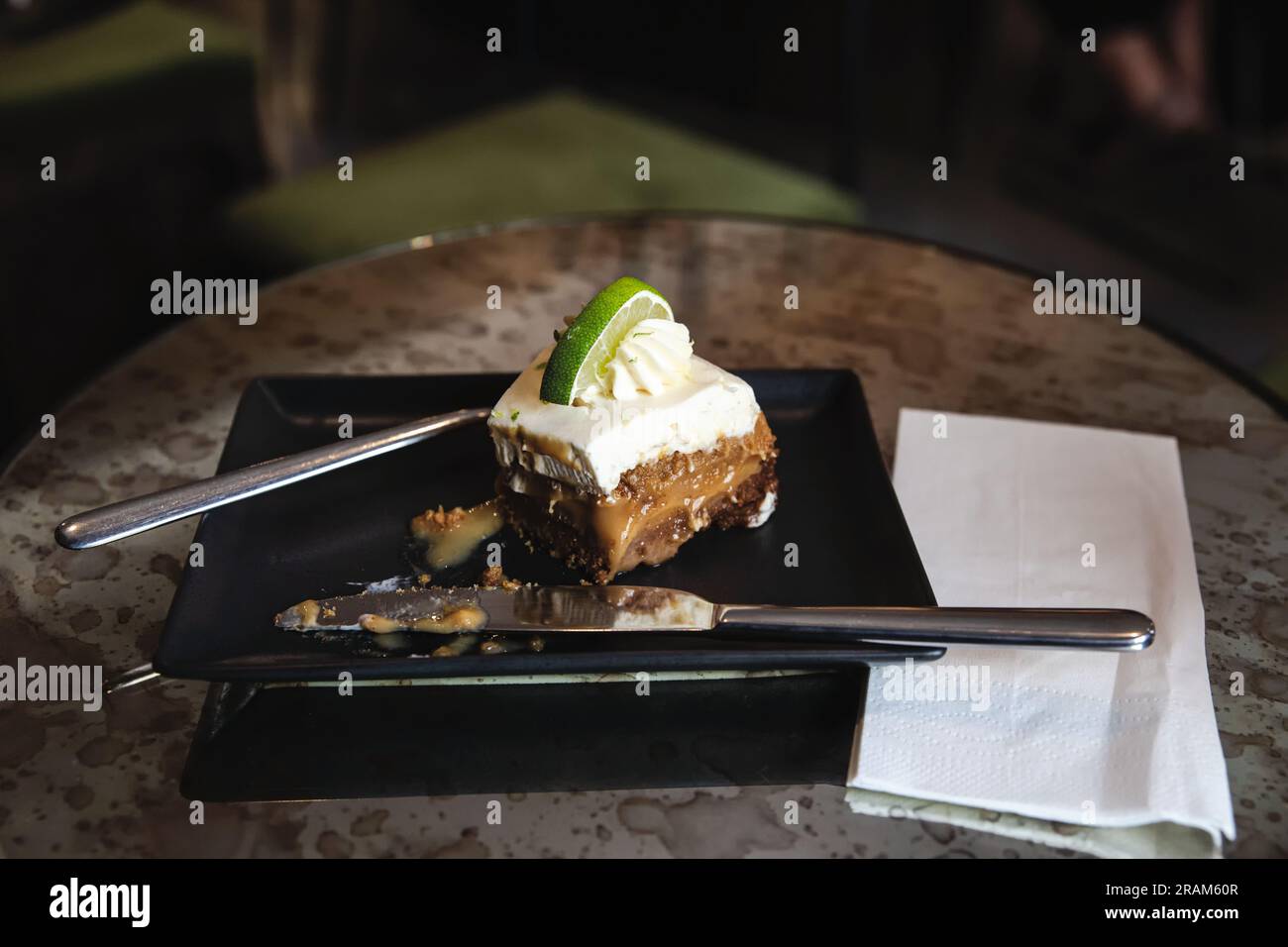 Halb gefressene Zitronenkäse auf elegantem, schwarzem, quadratischem Teller. Stockfoto