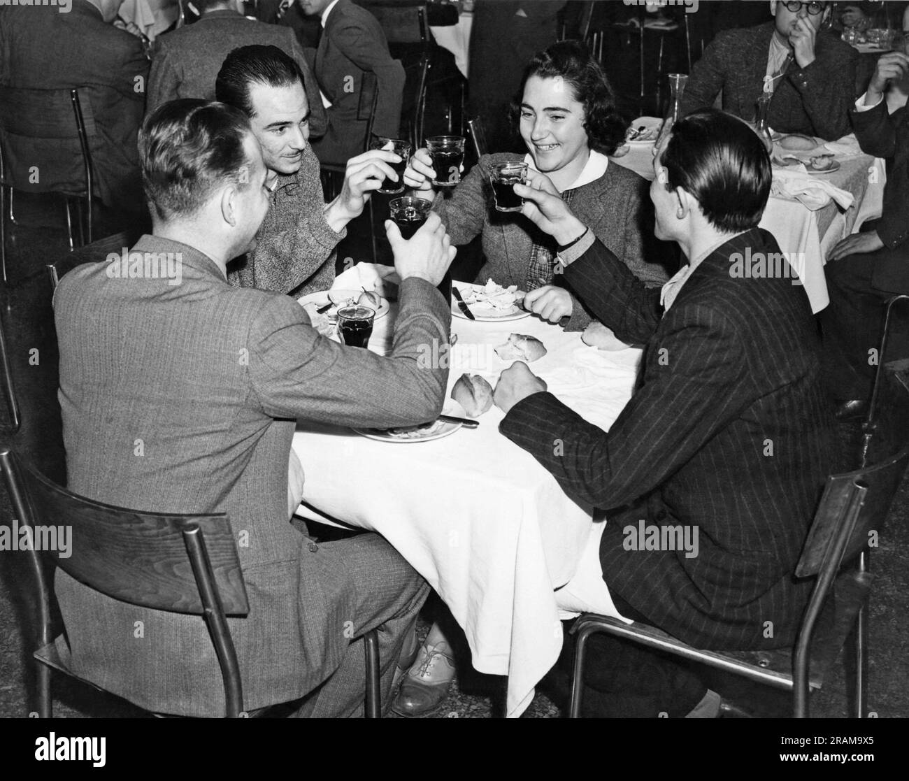 New York, New York: ca. 1939. Vier Freunde stoßen bei einem Abendessen in einem Restaurant auf einen Toast an. Stockfoto