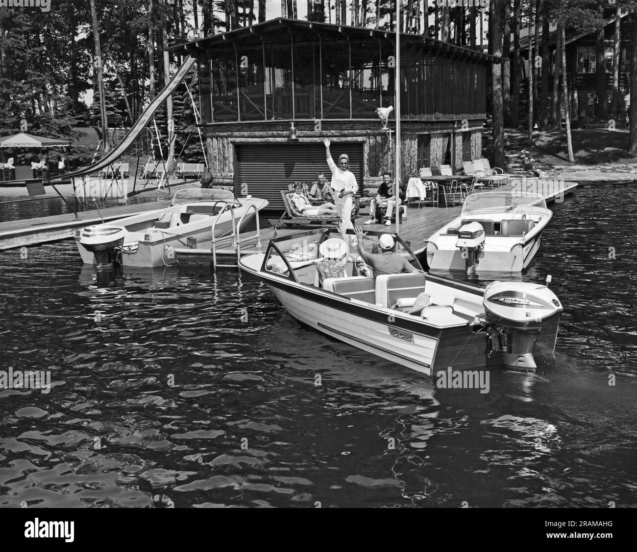 Vereinigte Staaten: c. 1960. Ein Paar kommt mit dem Motorboot an, um sich anderen auf dem Deck anzuschließen. Stockfoto