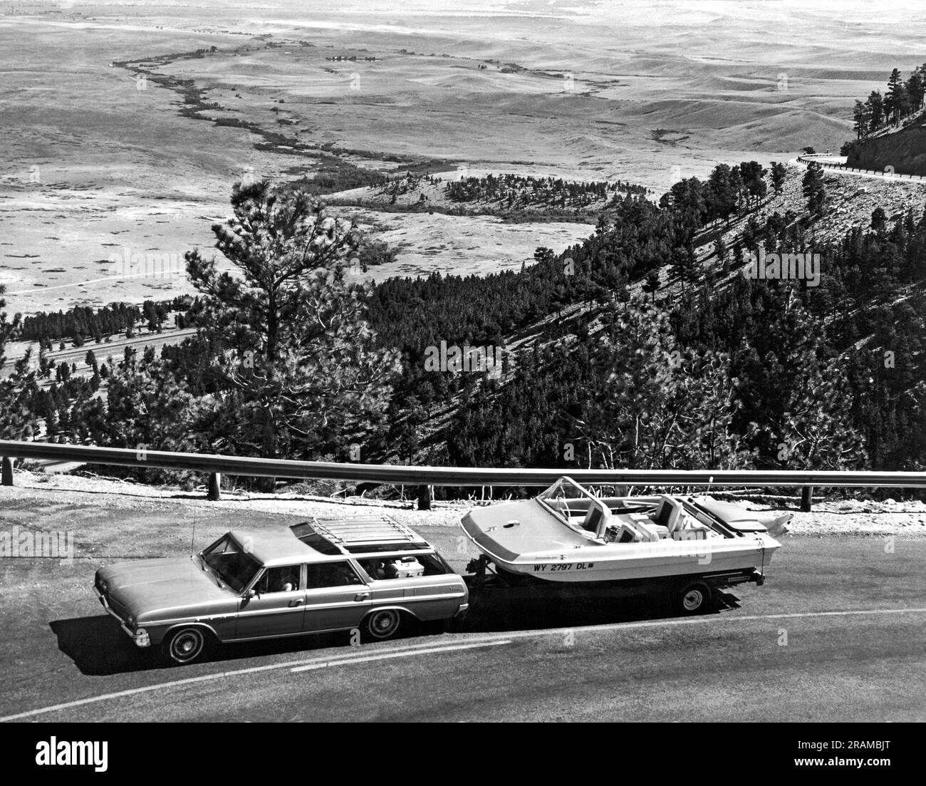 Vereinigte Staaten: c. 1960. Ein Kombi, der ein Motorboot schleppt, fährt vom Tal unten im Hintergrund in die Berge. Stockfoto