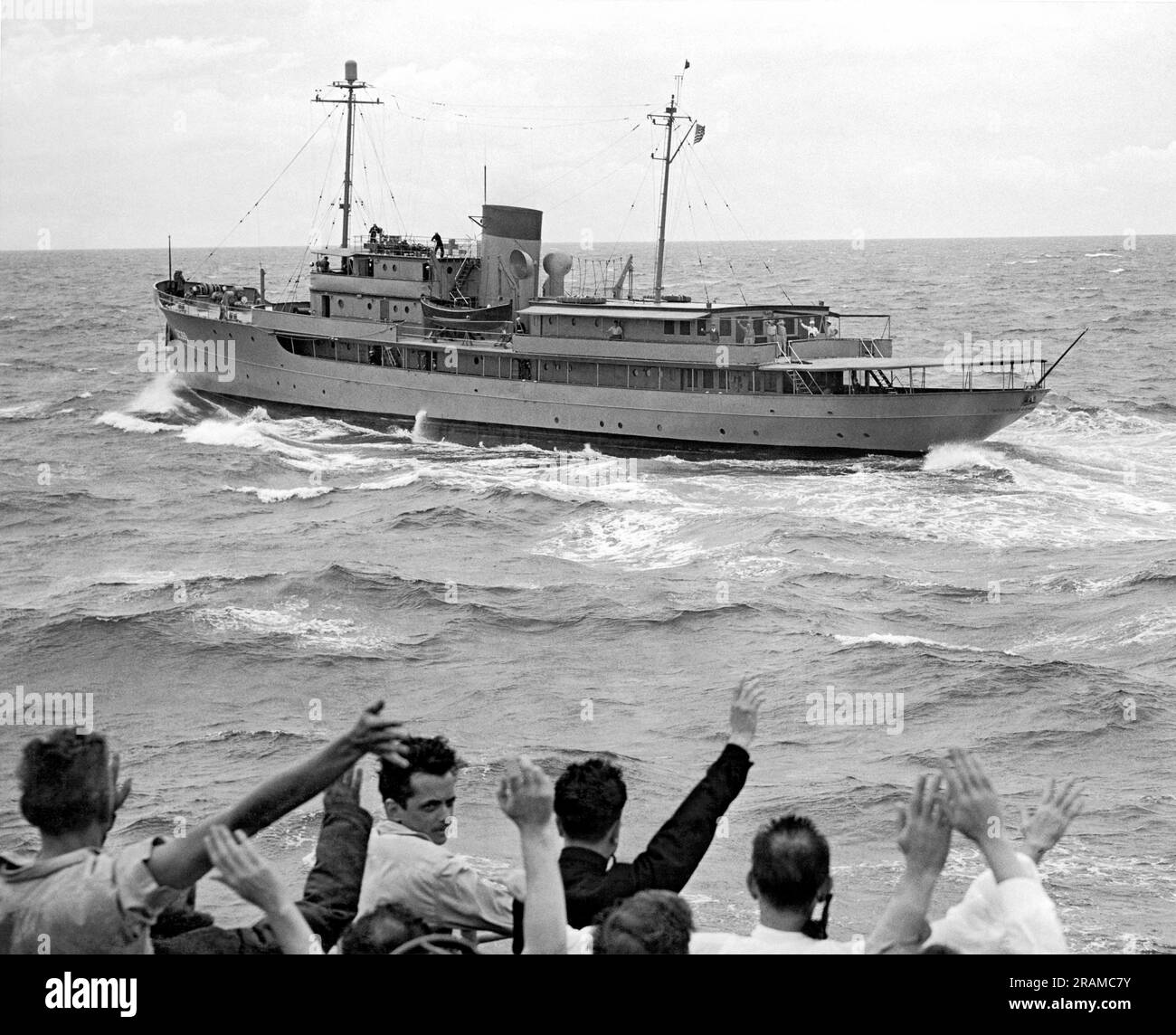 Atlantik: August 1946. Die Präsidentenyacht „Williamsburg“ hat eine raue Fahrt in rauen Meeren, während sie mit Präsident Truman an Bord nach Bermuda fährt. Reporter winken dem Präsidenten vom Escortschiff USS Weiss zu. Stockfoto