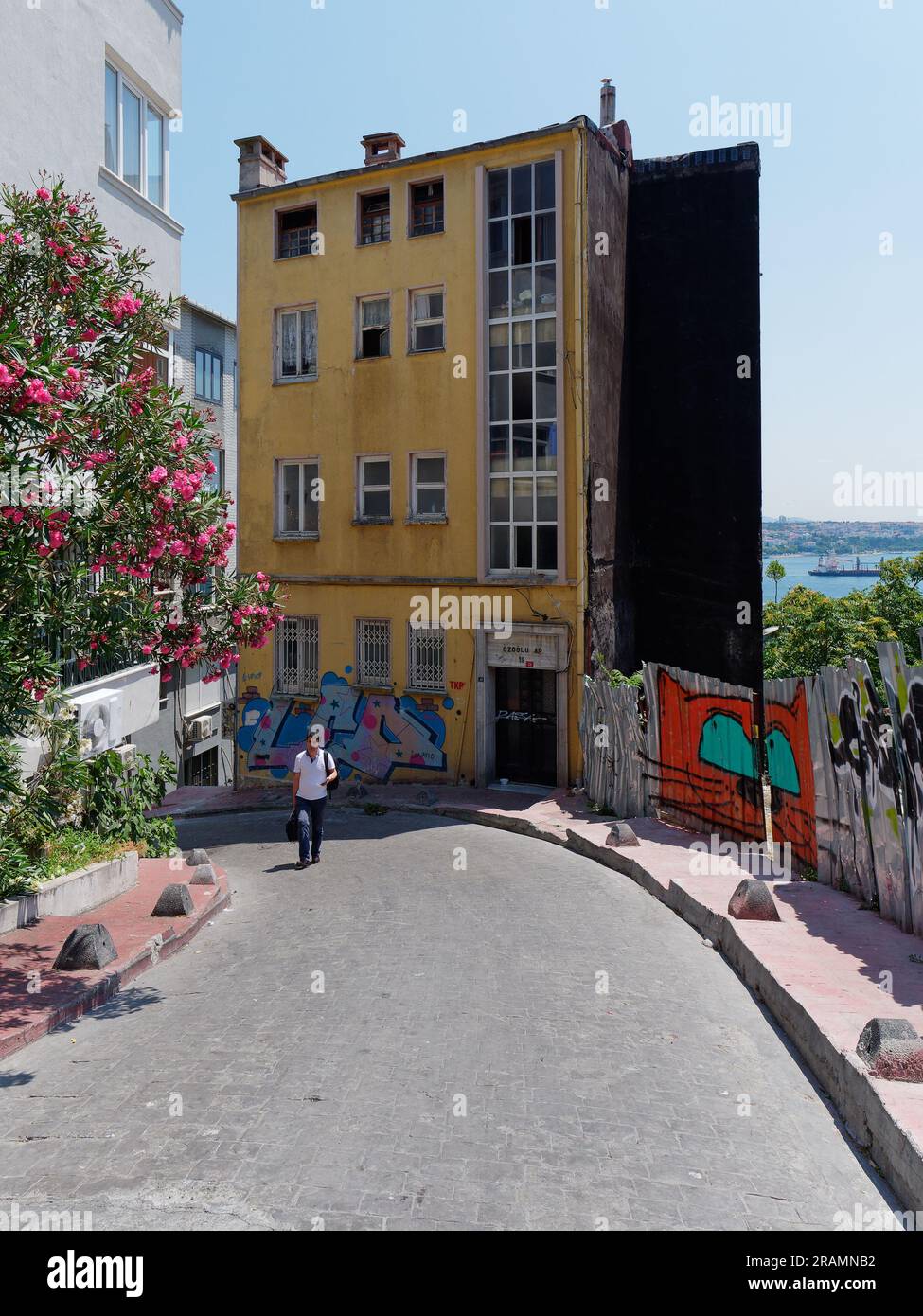 Fußgänger spazieren entlang einer farbenfrohen Straße in Istanbul mit einem gelben Gebäude und einer orangen Katze, die an einer Wand neben dem Bürgersteig, Truthahn, gemalt ist Stockfoto