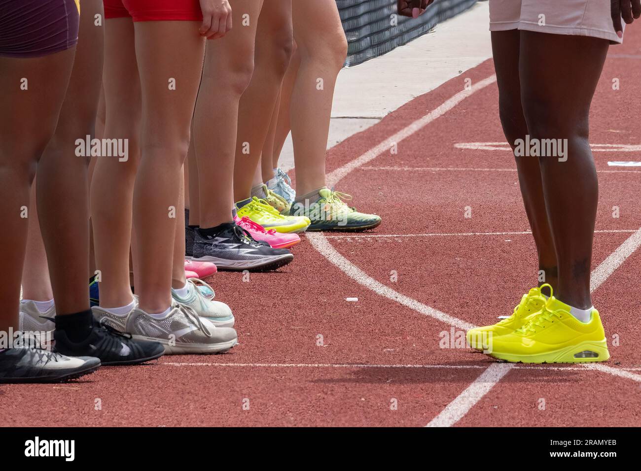 Track- und Feldläufer und Trainer haben sich vor dem Rennen auf der Rennstrecke aufgestellt und zeigen nur Beine und Stollen. Stockfoto