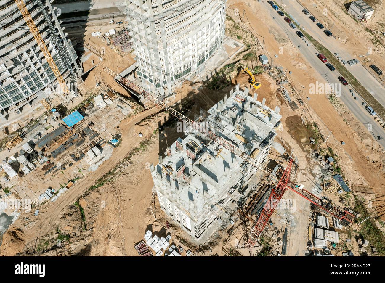 Vielbeschäftigte Baustelle. Kräne und Wohnhäuser in Hochhäusern befinden sich im Bau. Luftaufnahme von oben an sonnigen Tagen. Stockfoto