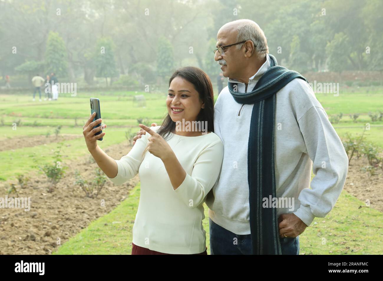 Indianischer fröhlicher Großvater, der mit ihrer Enkelin ins Mobile schaut. Sie sehen beide glücklich und fröhlich aus. Videoanrufe mit Familienangehörigen im Ausland. Stockfoto