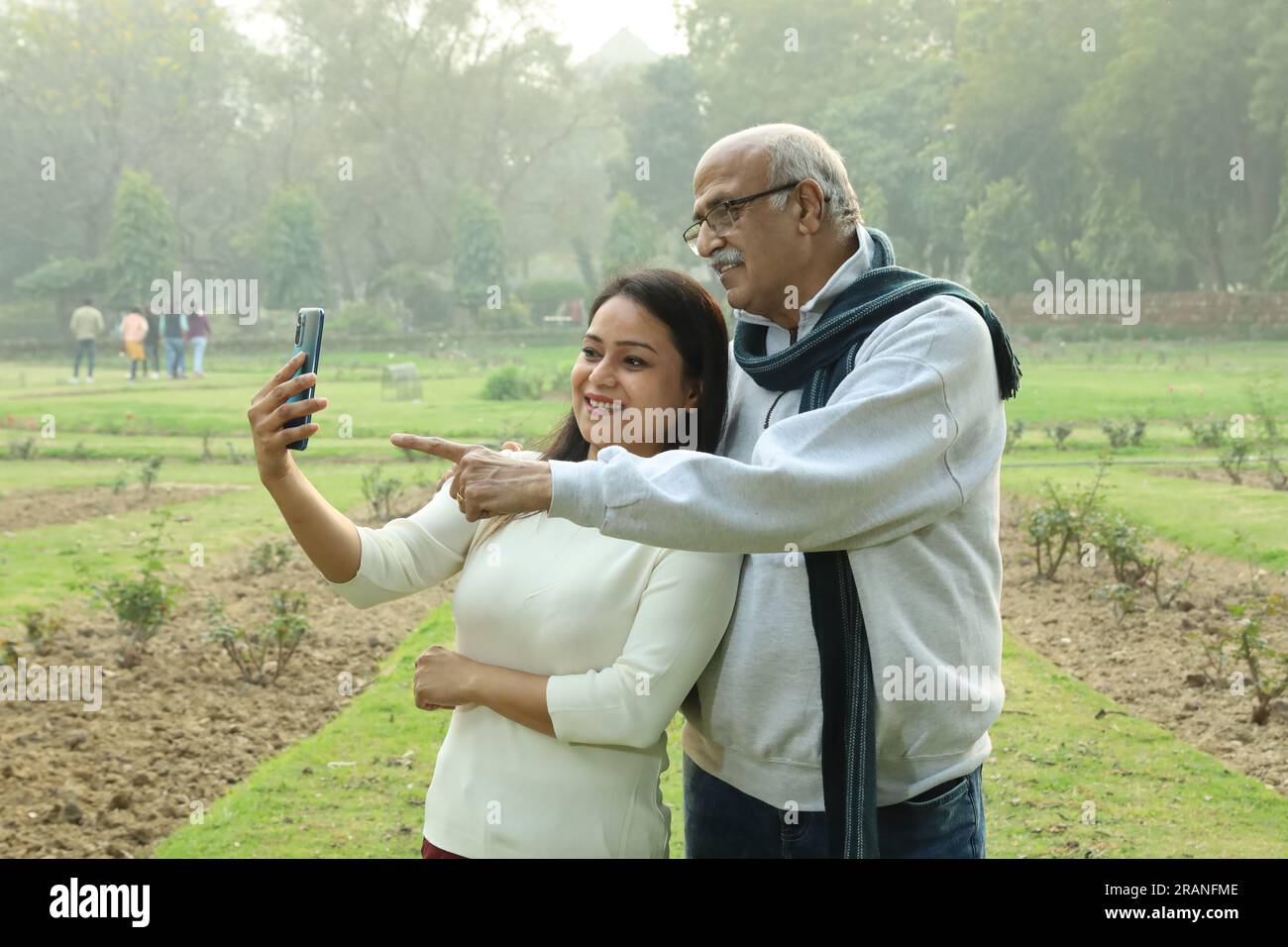 Indianischer fröhlicher Großvater, der mit ihrer Enkelin ins Mobile schaut. Sie sehen beide glücklich und fröhlich aus. Videoanrufe mit Familienangehörigen im Ausland. Stockfoto