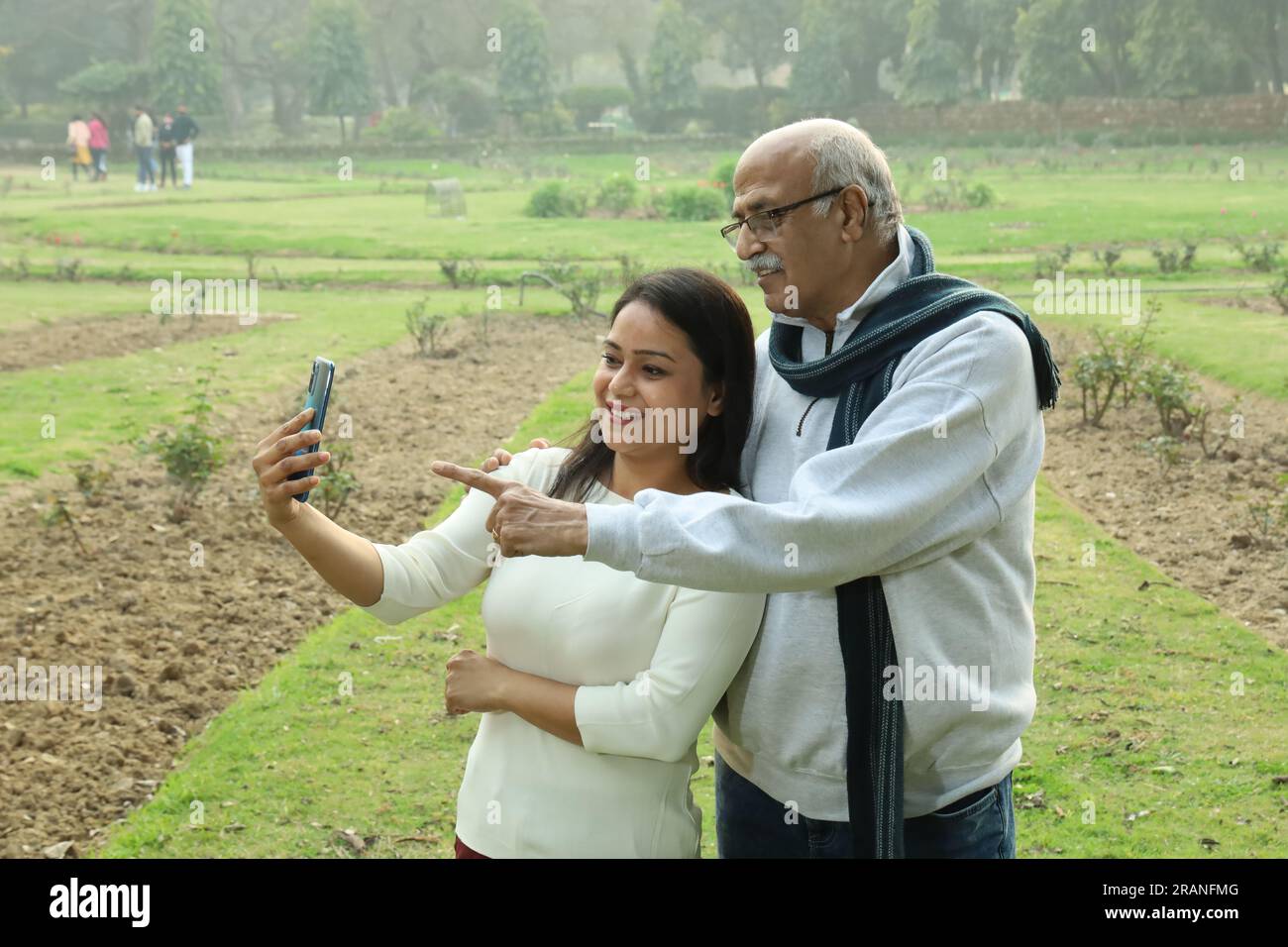 Indianischer fröhlicher Großvater, der mit ihrer Enkelin ins Mobile schaut. Sie sehen beide glücklich und fröhlich aus. Videoanrufe mit Familienangehörigen im Ausland. Stockfoto