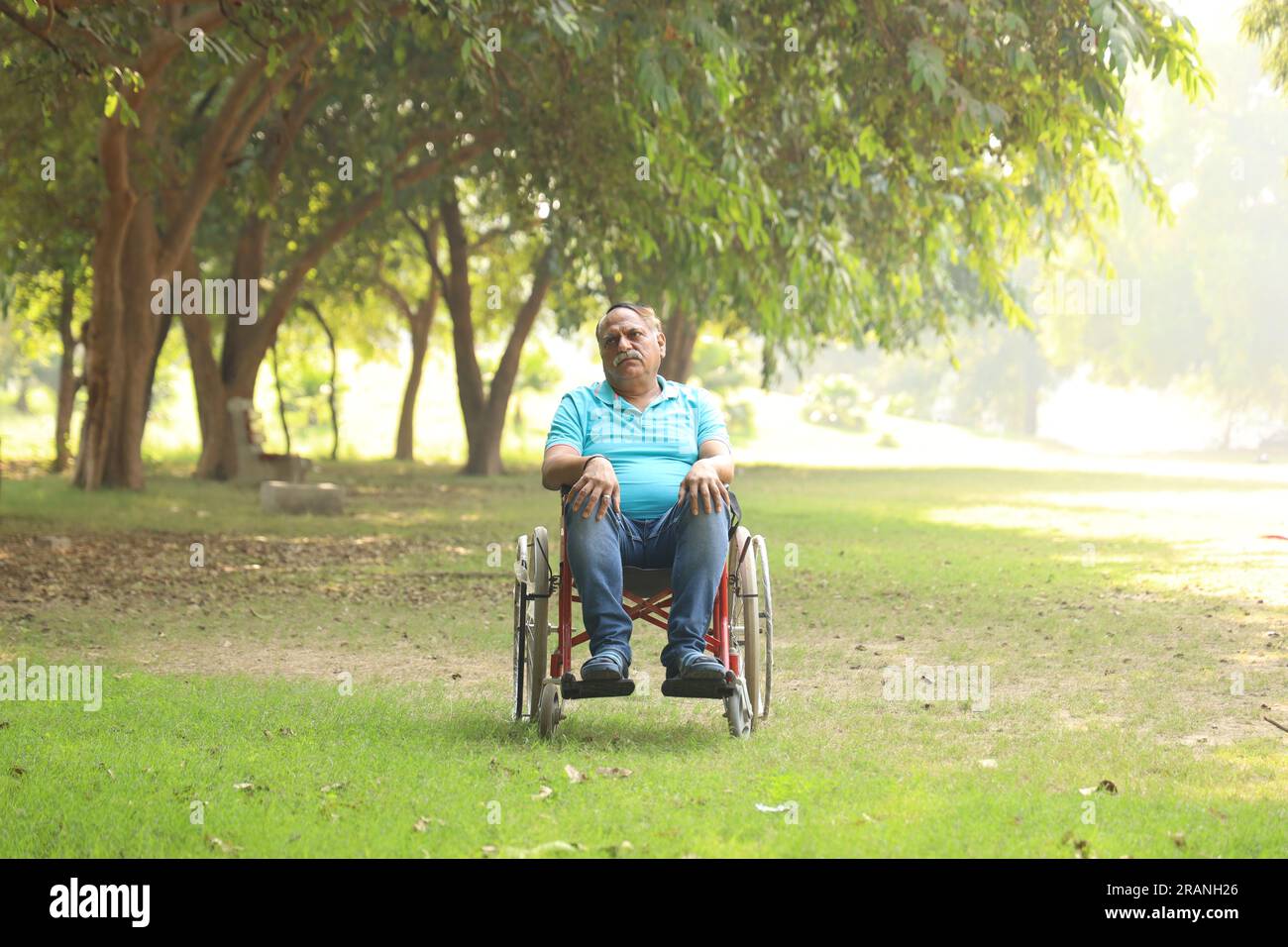 Indischer Seniorpatient im Krankenhausgarten auf dem Rollstuhl sitzend. Der Patient ist im Freien nicht in der Frischluftatmosphäre zu gehen. Stockfoto