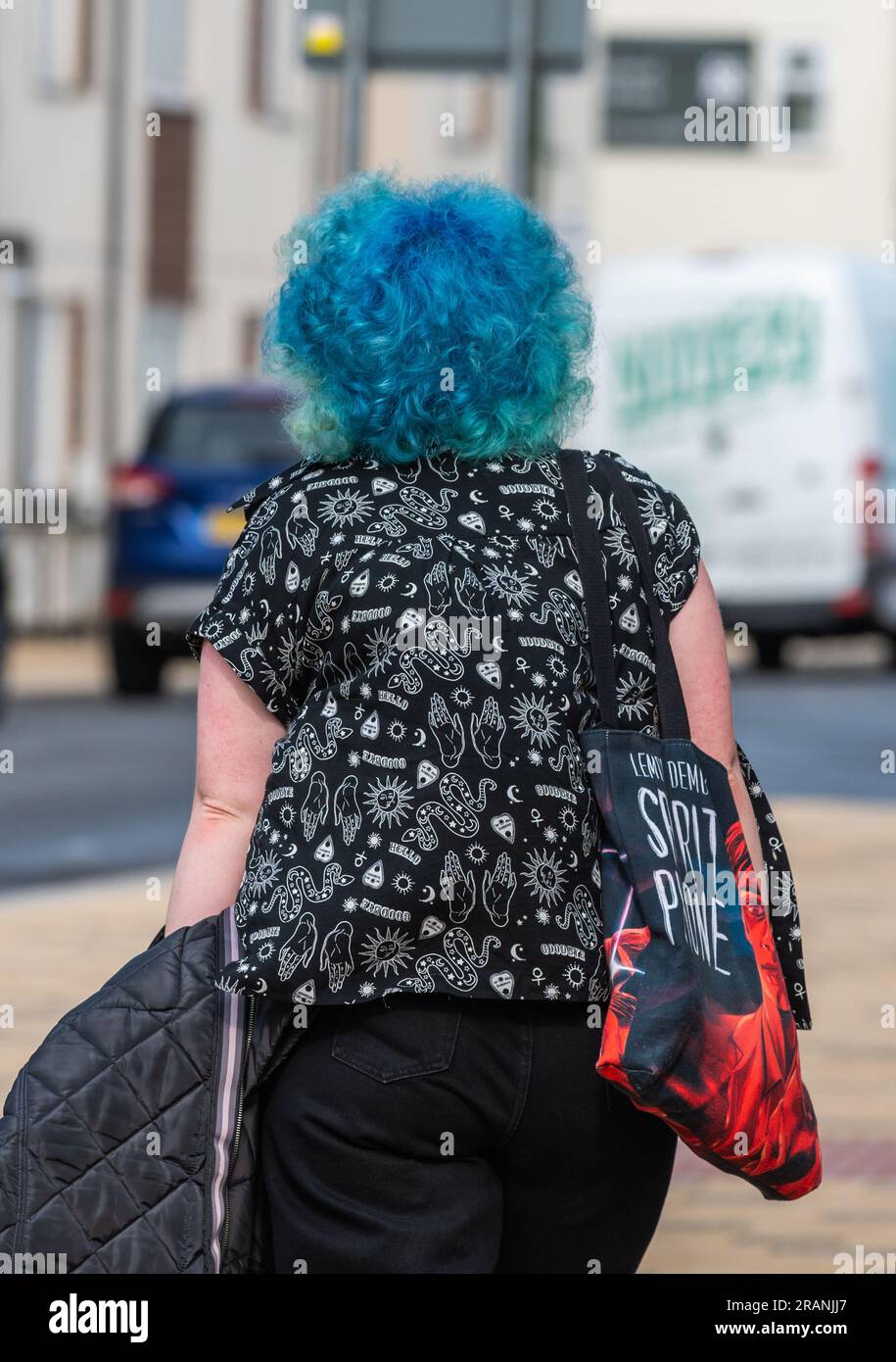 Junge, moderne Frau mit bunten blauen Haaren, die im Sommer in England auf einem Bürgersteig spaziert. Porträt. Stockfoto
