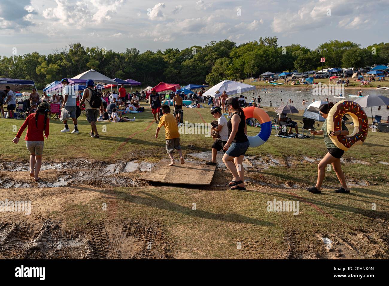 Little Elm, Texas, USA. 4. Juli 2023. 7/4/23 Little Elm, Texas - Tausende von mutigen extremen Hitzewellen und Gewitter zur Feier des Unabhängigkeitstages im Little Elm Lake Park mit Schwimmen, Live-Musik und Feuerwerk. Dieses Jahr ist eines der geschäftigsten Jubiläen, die die Stadt je gesehen hat. Die Menschen überqueren einen überfluteten Weg von Stürmen, die die Stadt am Vortag heimsuchten. (Kreditbild: © Chris Rusanowsky/ZUMA Press Wire) NUR REDAKTIONELLE VERWENDUNG! Nicht für den kommerziellen GEBRAUCH! Stockfoto