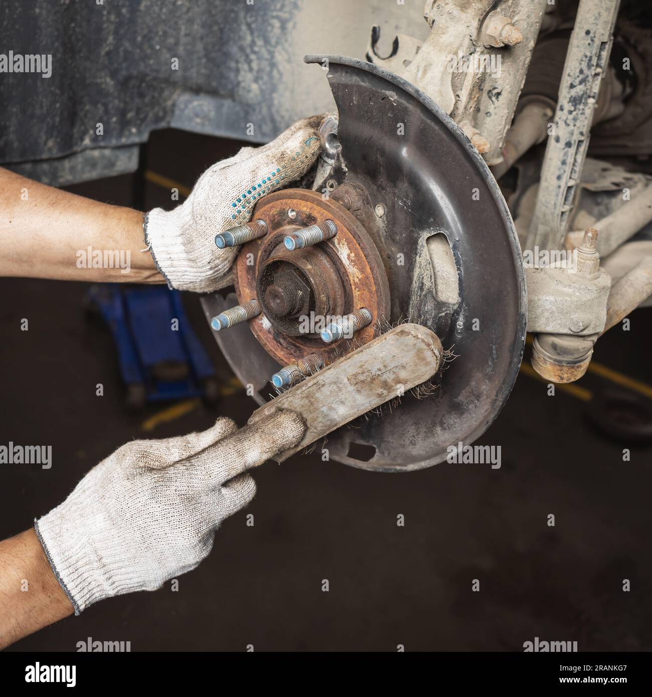 Ein Automechaniker wartet die Bremsanlage eines Fahrzeugs in einer Werkstatt, bevor er eine neue Bremsscheibe einbaut, reinigt Teile und Baugruppen mit einem metallisierten b Stockfoto