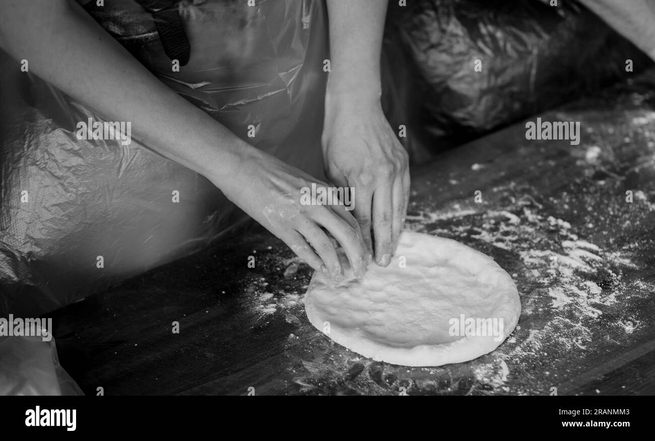 Verarbeitung des Pizzateigs durch den Pizzahersteller. Traditionelles italienisches Essen Stockfoto