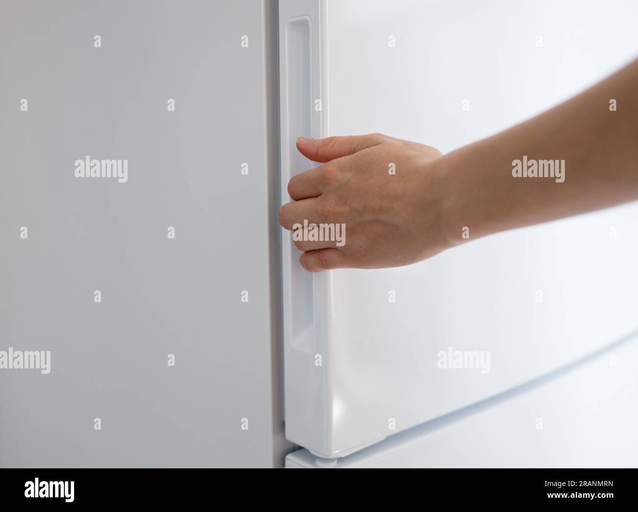 Frau öffnet modernen weißen Kühlschrank. Weiblicher Kühlschrank mit Handöffnung Stockfoto