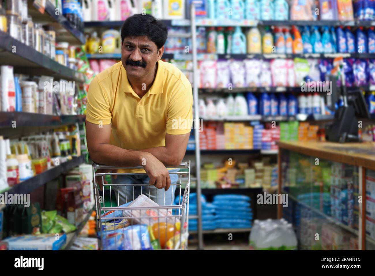 Ein Indianer, der in einem Supermarkt einkauft. Lebensmittel für zu Hause in einem Supermarkt kaufen. Überlegen, was ich kaufen soll Stockfoto