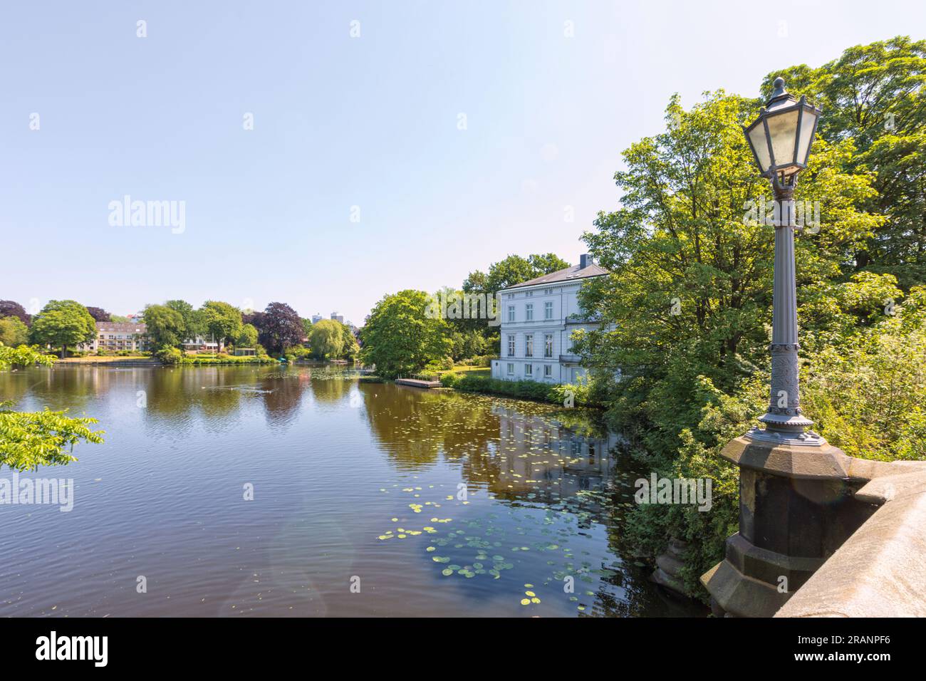 Feenteich, ein Nebenfluss der Alster in Hamburg, an einem sonnigen Tag, alter Lampenpfosten auf der Brücke im Vordergrund Stockfoto