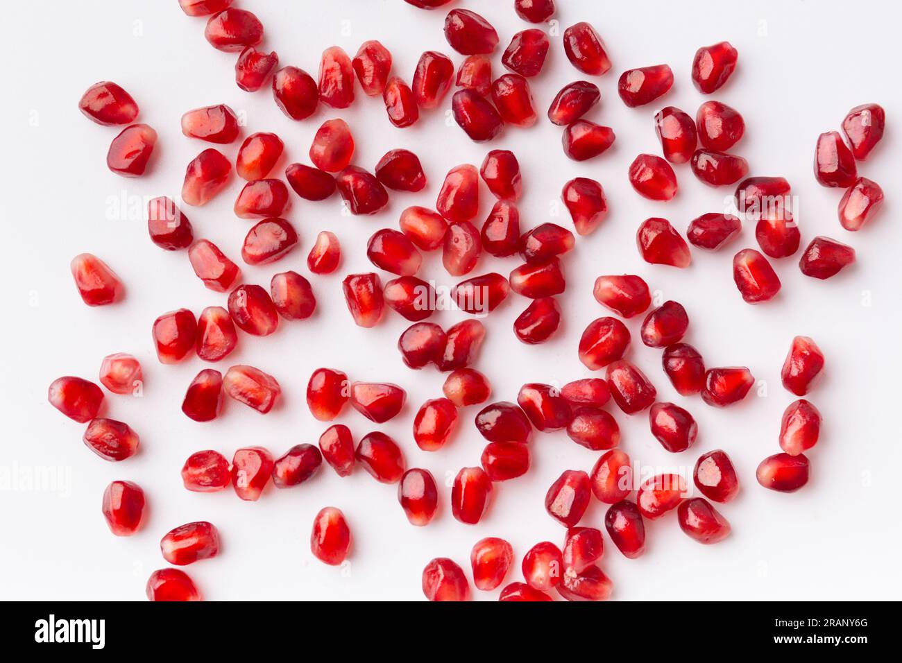 Große reife Granatapfelsamen auf weißem Hintergrund, Draufsicht, flach liegend, Hintergrund von Granatapfelsamen. Stockfoto