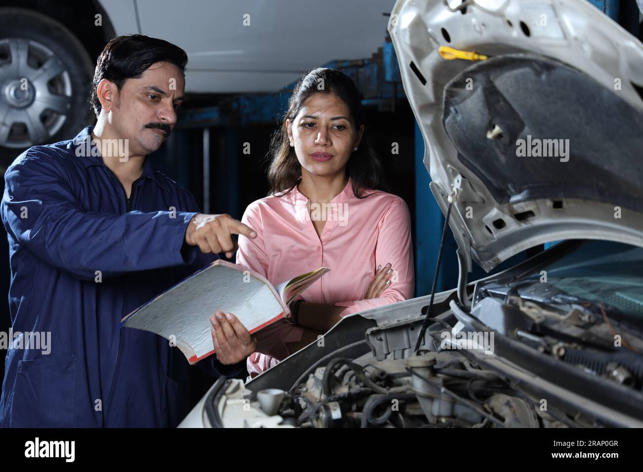 Glückliche Kundin zeigt Daumen hoch, weil sie ihr Auto pünktlich repariert hat. Darstellung des Kundenvertrauens und der Kundenzufriedenheit gegenüber der Tankstelle. Stockfoto