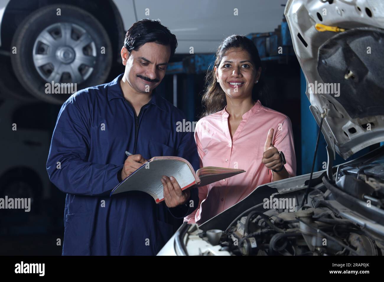 Glückliche Kundin zeigt Daumen hoch, weil sie ihr Auto pünktlich repariert hat. Darstellung des Kundenvertrauens und der Kundenzufriedenheit gegenüber der Tankstelle. Stockfoto