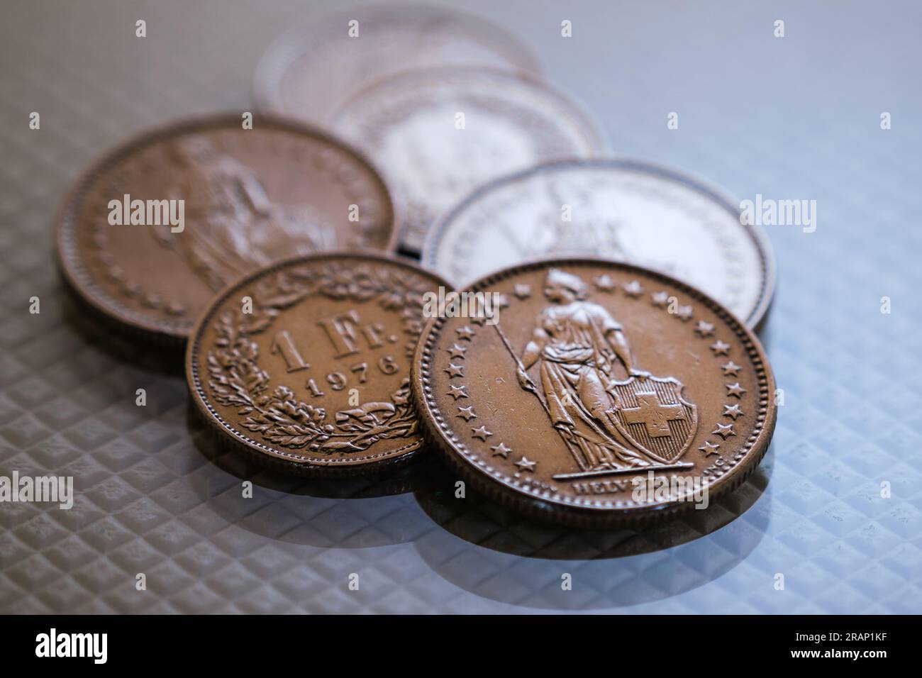 Ein paar Schweizer-Franken-Münzen, die auf einer glänzenden, weiß strukturierten Basis liegen. Stockfoto