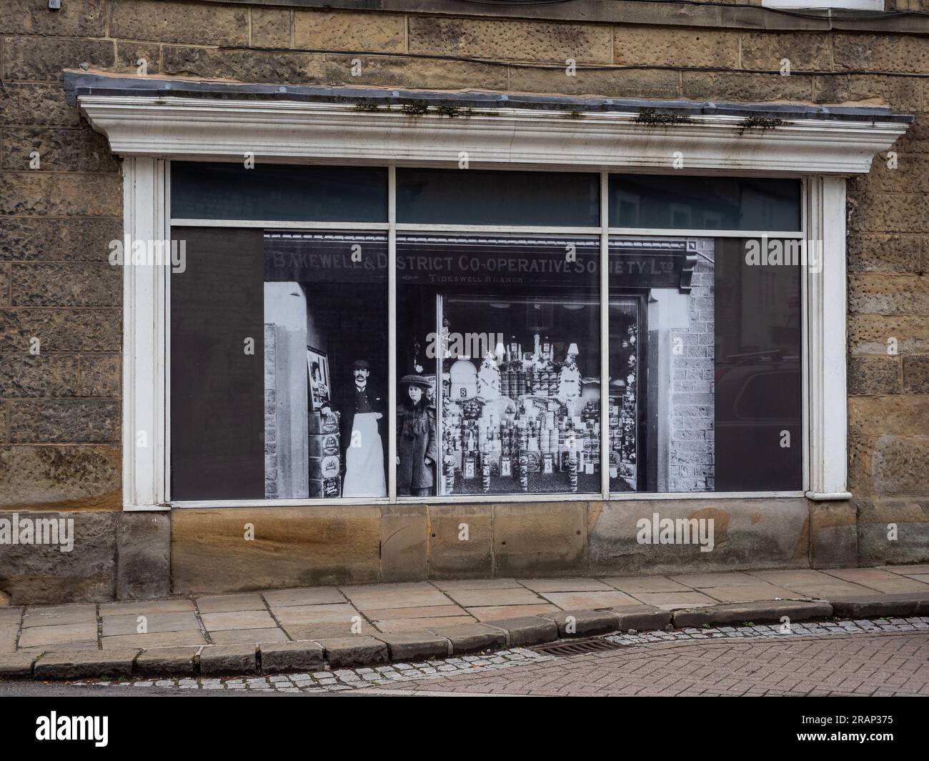 Schaufensterausstellung des Co-op-Stores in Tideswell, Derbyshire, Großbritannien; ein historisches Foto des Stores. Stockfoto