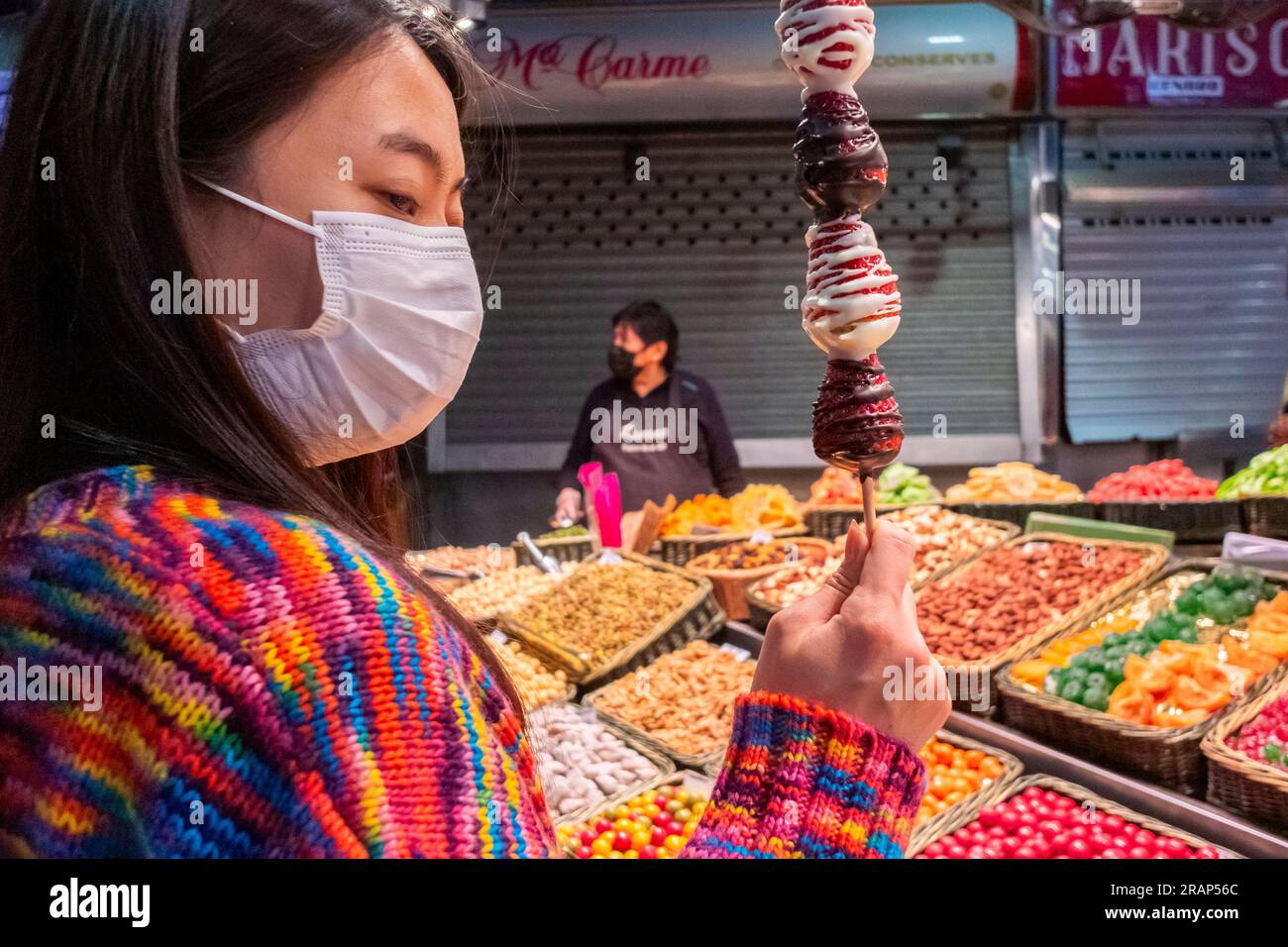 Barcelona, Spanien, chinesischer Tourist in Maske, Essen lokaler Süßigkeiten am Stick, traditioneller spanischer Lebensmittelmarkt, Zentrum Stadt, St. Josep, 'La Boqueria' BARCELONA Markt Stockfoto