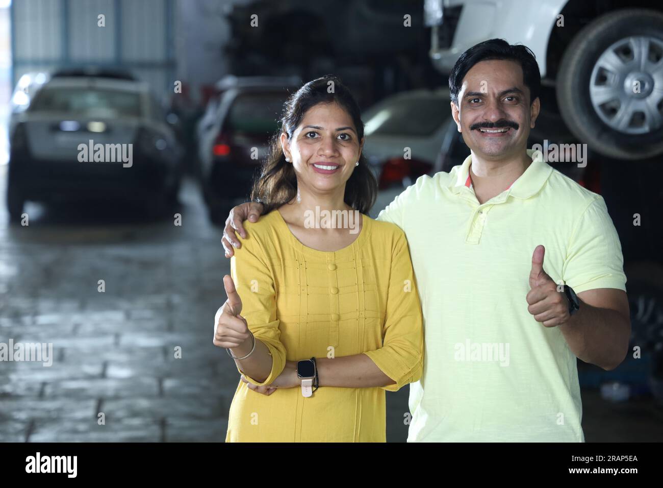 Indische glückliche Kundin, die Daumen hoch zeigt, weil sie das Auto repariert hat. Darstellung des Kundenvertrauens und der Kundenzufriedenheit gegenüber der Tankstelle Stockfoto