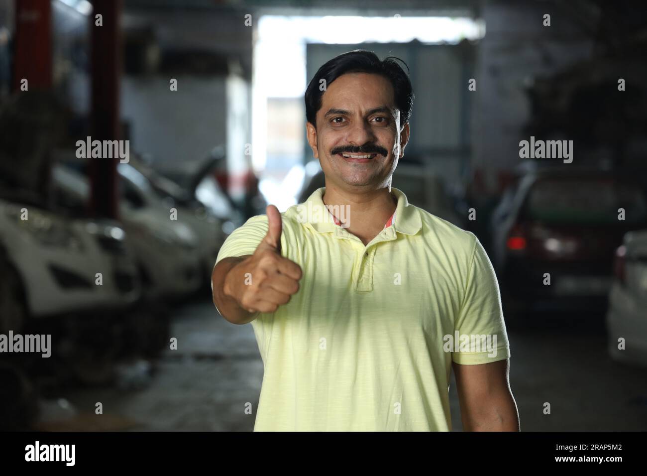 Indische glückliche Kundin, die Daumen hoch zeigt, weil sie das Auto repariert hat. Darstellung des Kundenvertrauens und der Kundenzufriedenheit gegenüber der Tankstelle Stockfoto