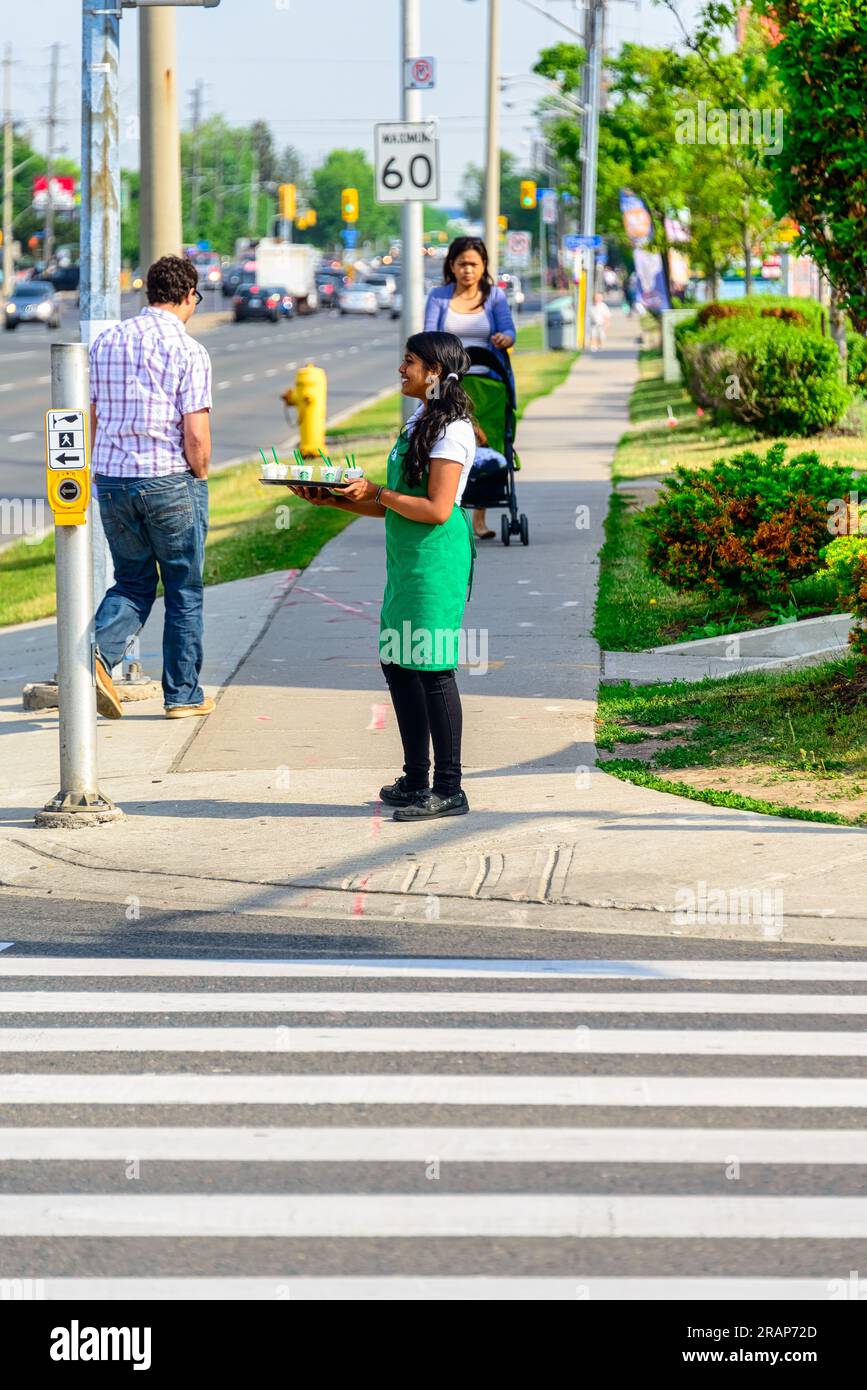 Eine junge Frau serviert Starbucks-Kaffee auf einem Bürgersteig. Stockfoto