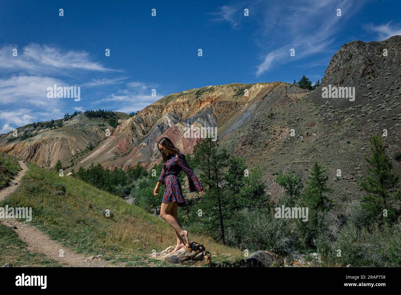 Eine junge Frau in einem kurzen Kleid steht neben einem Wanderweg vor der Kulisse des berühmten Wahrzeichens Altai Mars im Canyon. Sommerurlaub CONT Stockfoto